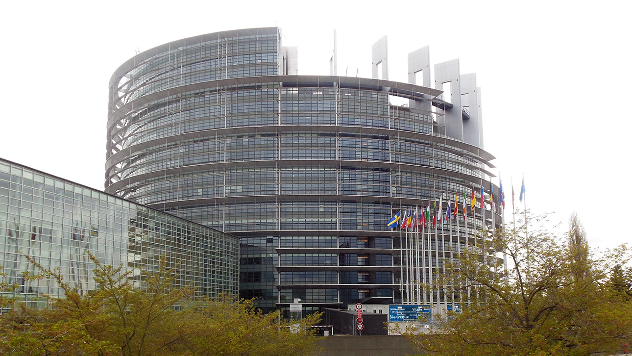 Blick auf das EU Europäische Parlament in Straßburg. Im Vordergrund wehen Fahnen der EU-Mitgliedsstaaten.
