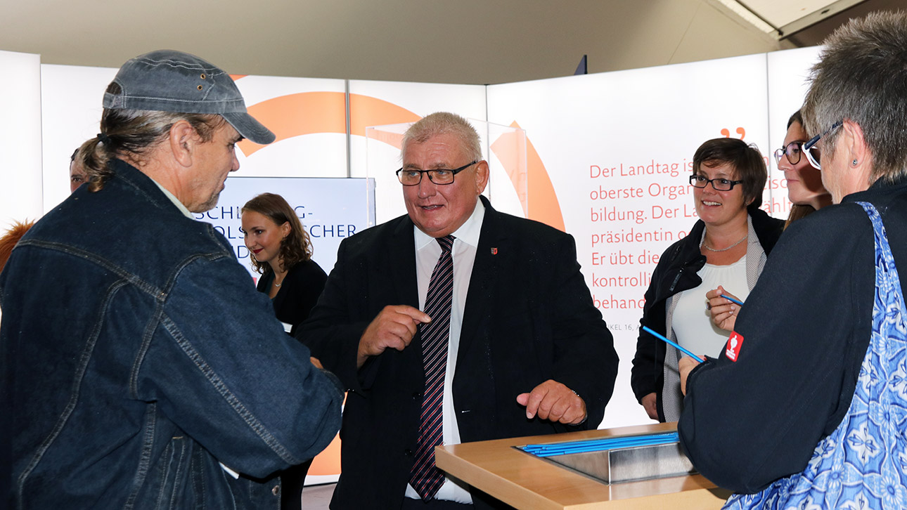 Landtagspräsident Klaus Schlie spricht am Messestand des Landtages mit einem Bürger.