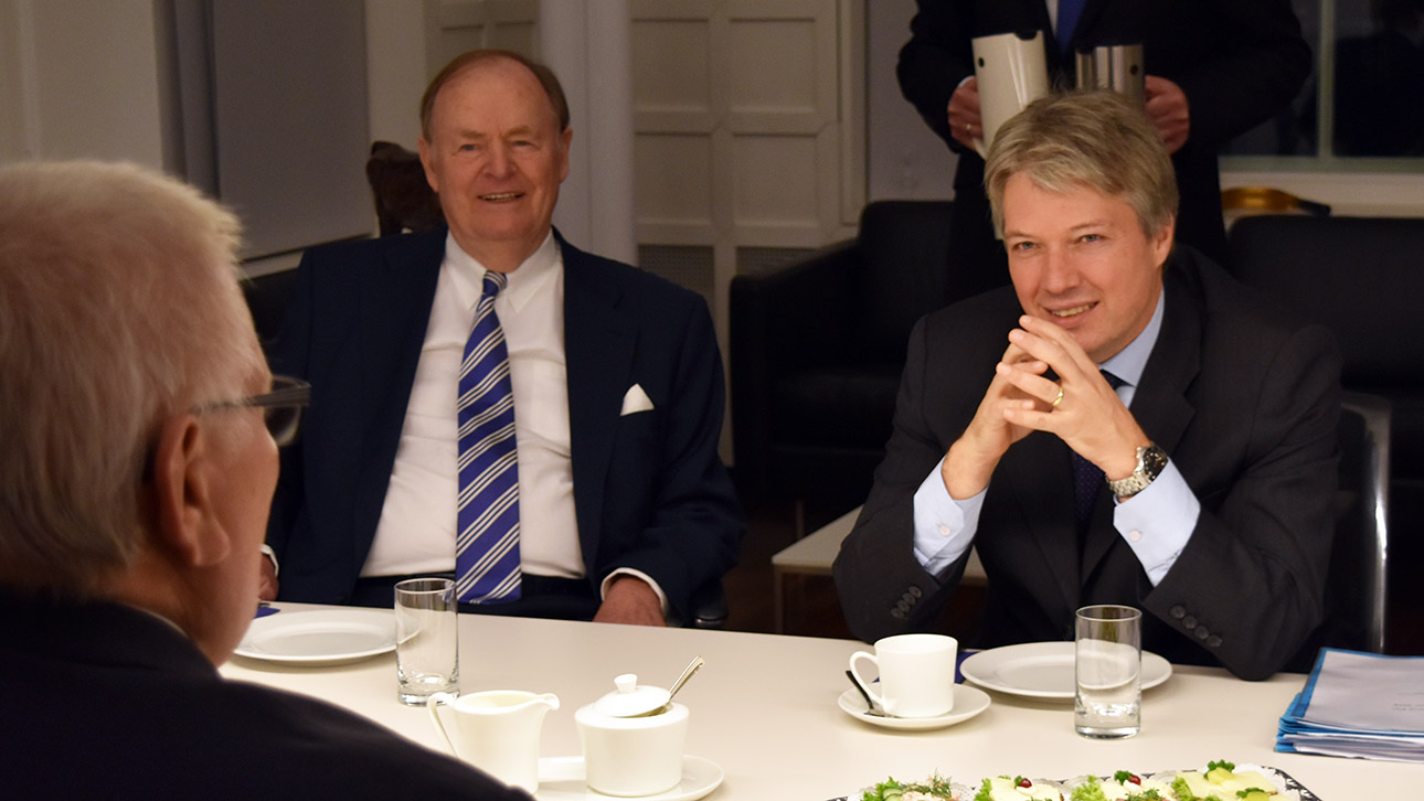 Landtagspräsident Klaus Schlie und der stellvertretende Botschafter Österreichs, Andreas Somogyi, sitzen sich an einem großen Tisch im Dienstzimmer des Präsidenten gegenüber und schauen sich an.