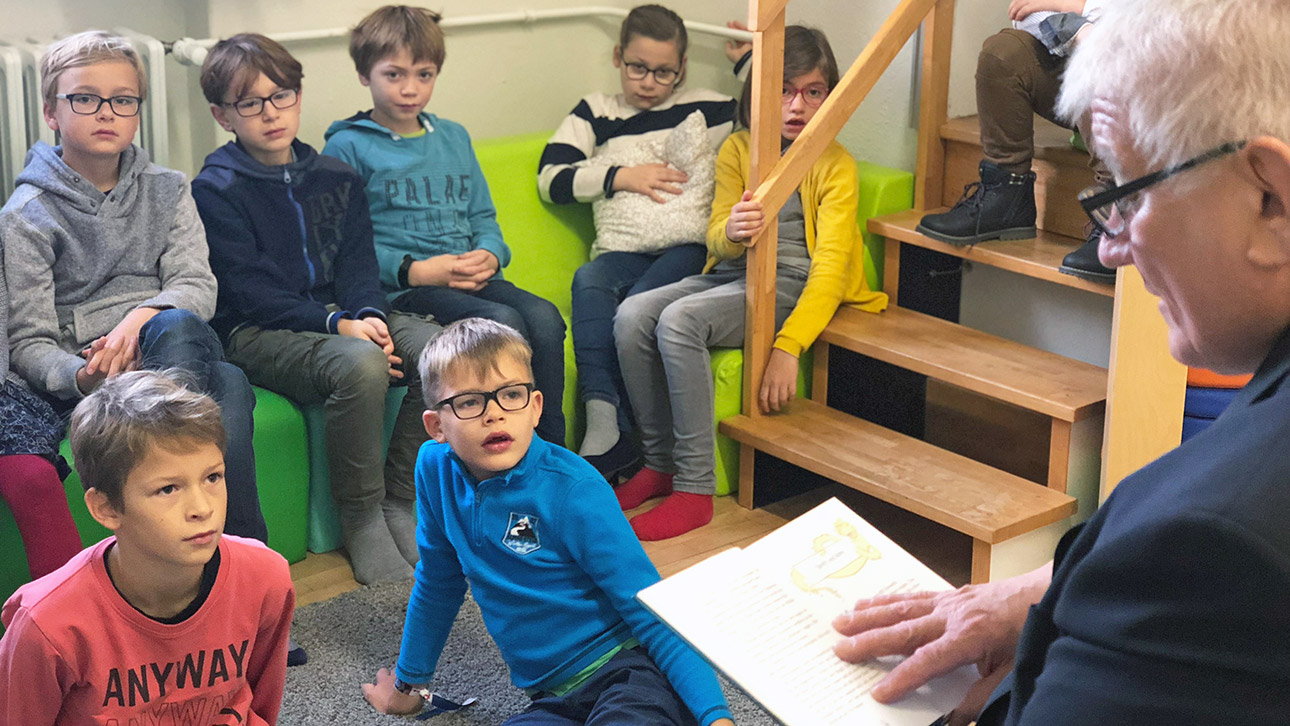 Landtagspräsident Schlie liest Kindern aus einem Buch vor.