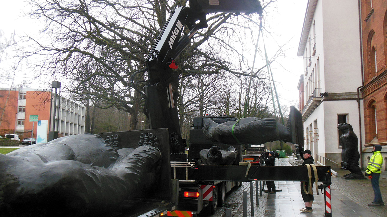 Eine über drei Meter große Gorilla-Skulptur hängt am Haken eines Krans, bereit zum Abtransport mit einem Schwerlastwagen.