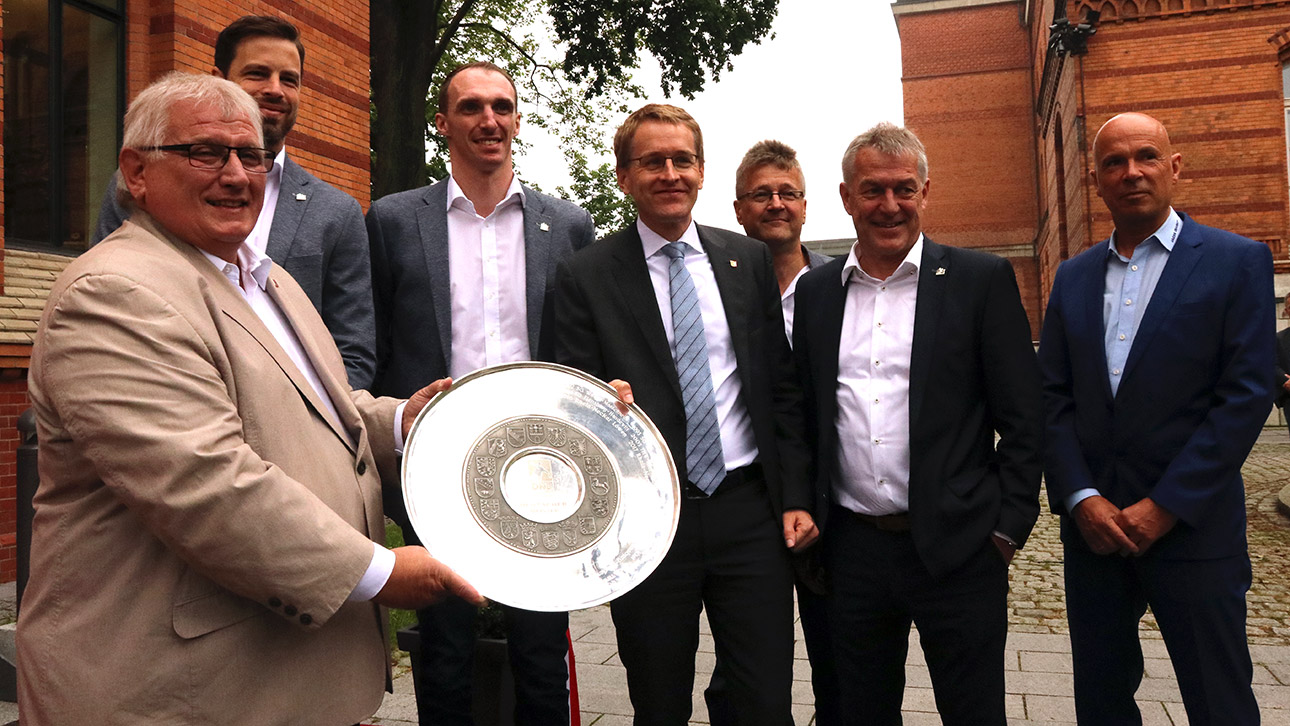 Landtagspräsident Klaus Schlie und Ministerpräsident Daniel Günther posieren mit den Handballern der SG Flensburg-Handewitt, da sie Deutscher Handballmeister geworden sind.