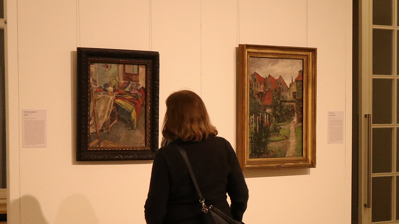 Eine Besucherin bewundert Gemälde der Brüder Heinrich Eduard Linde-Walther und Herrmann Linde.