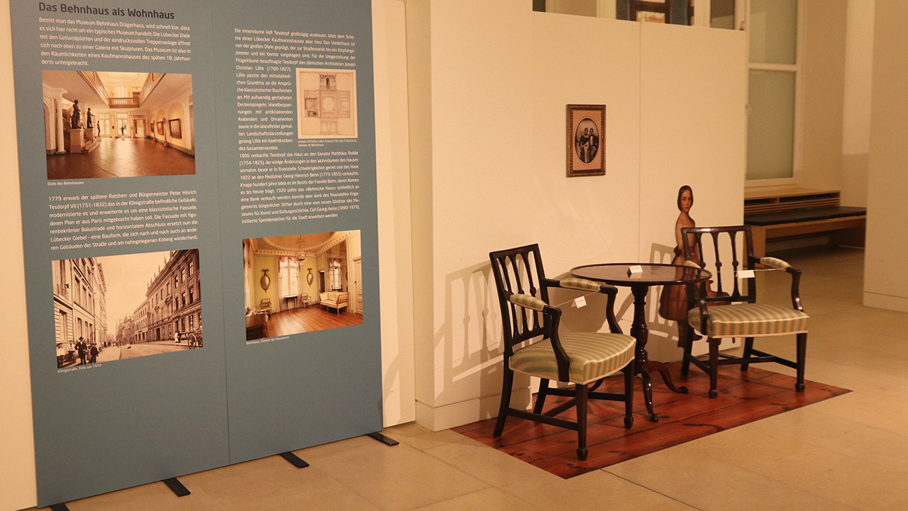 Auch historische Möbelstücke sind zu bewundern. Links eine Schautafel, die über das Interieur des Museums Behnhaus Drägerhaus Lübeck informiert.