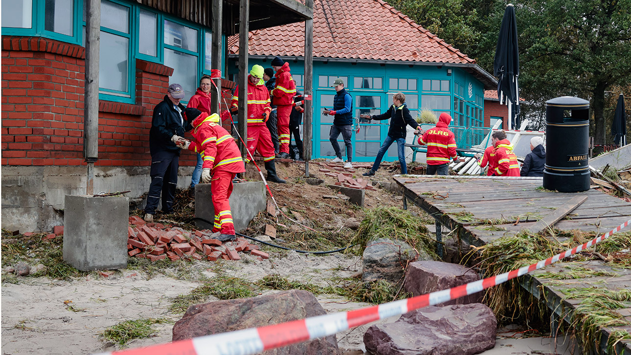 Mitarbeiter der Deutschen Lebens-Rettungs-Gesellschaft in Kiel bilden eine Kette, um herabgestürzte Steine einzusammeln.