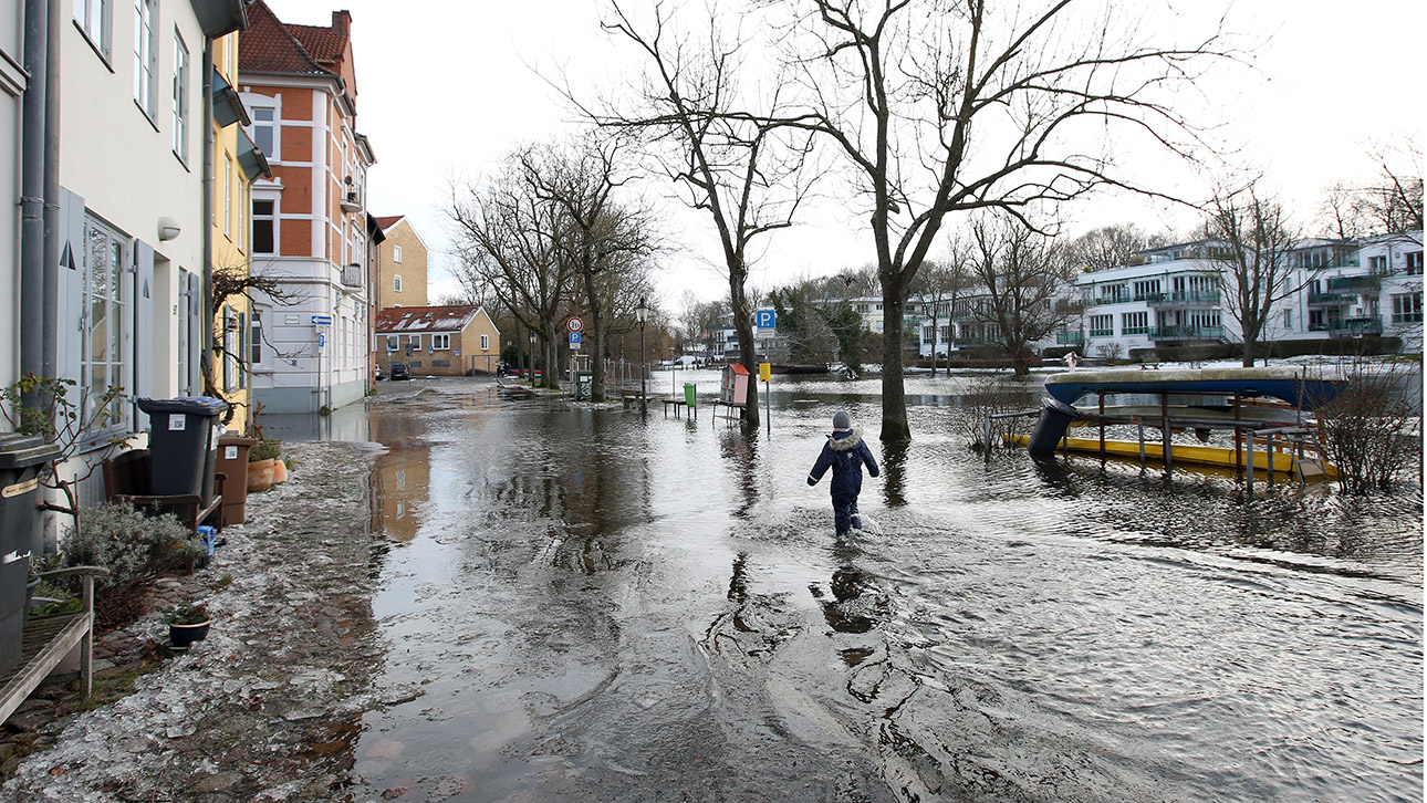 Das Wasser der Trave ist bei Hochwasser in der Altstadt von Lübeck über die Ufer getreten und überspült den Gehweg bis knapp an eine Häuserzeile. 