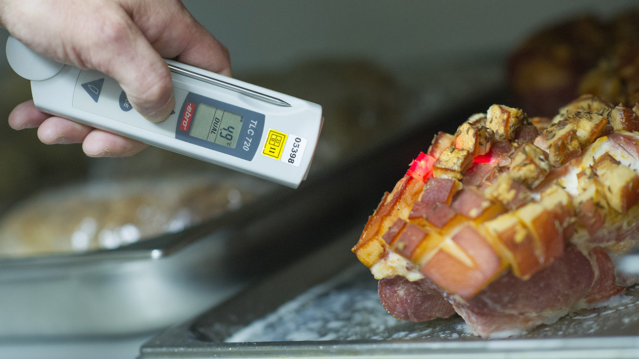 Ein Lebensmittelkontrolleur überprüft bei einer Betriebskontrolle die Temperatur einer Fleischware