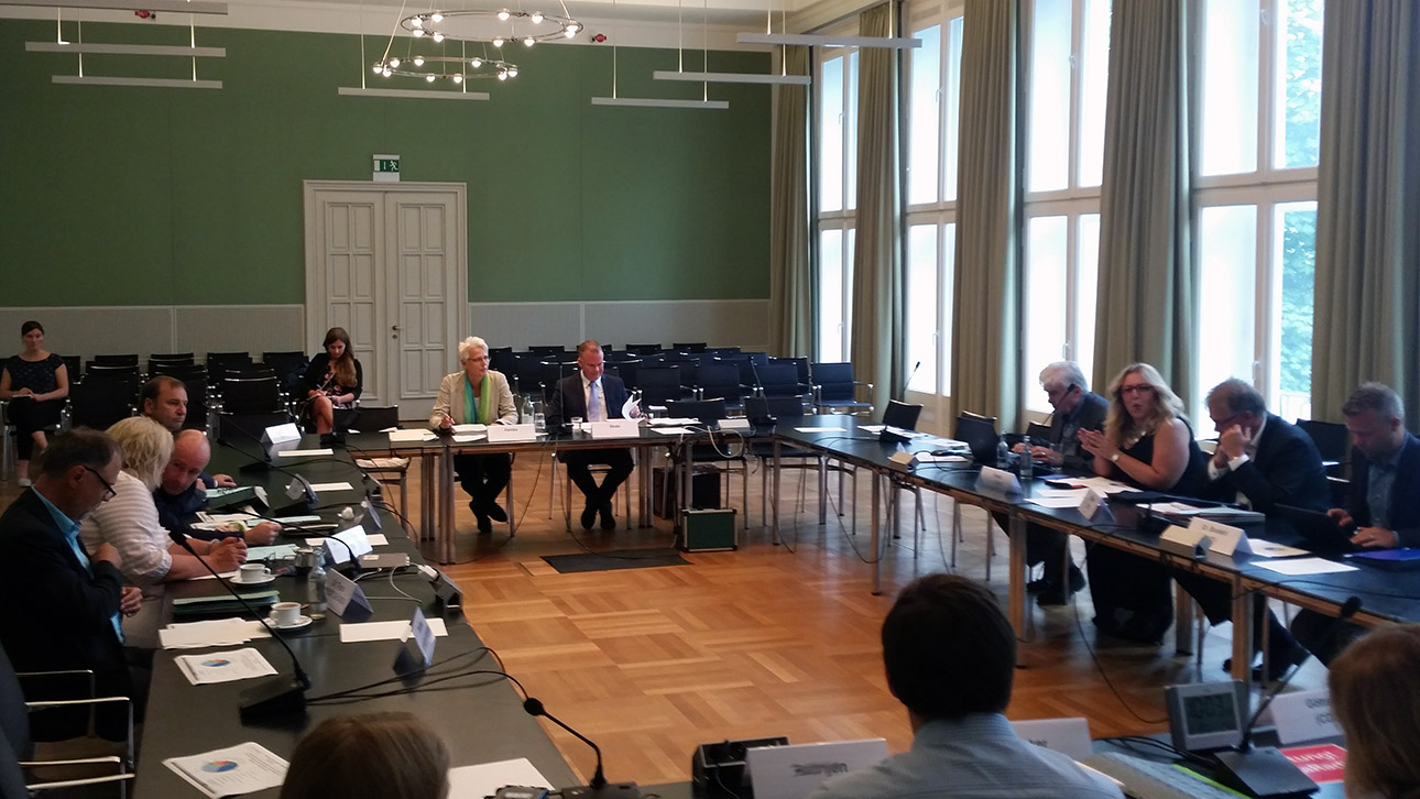 Die GEW-Vorsitzende Astrid Henke und der Referent aus dem Bildungsministerium Michael Stotz sitzen an der Stirnseite der Ausschusstische. Rechts und links sitzen Abgeordnete.