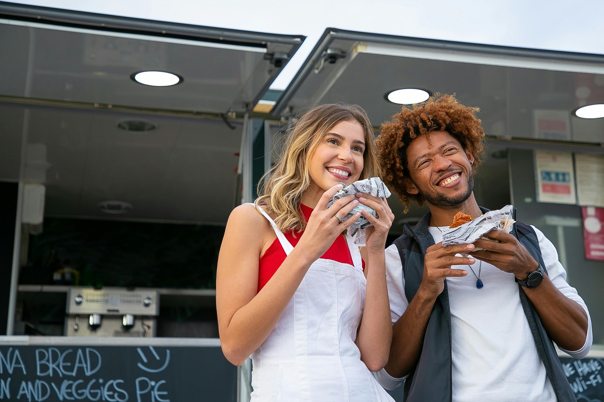 Zwei Personen mit Sandwich vor einem Foodtruck