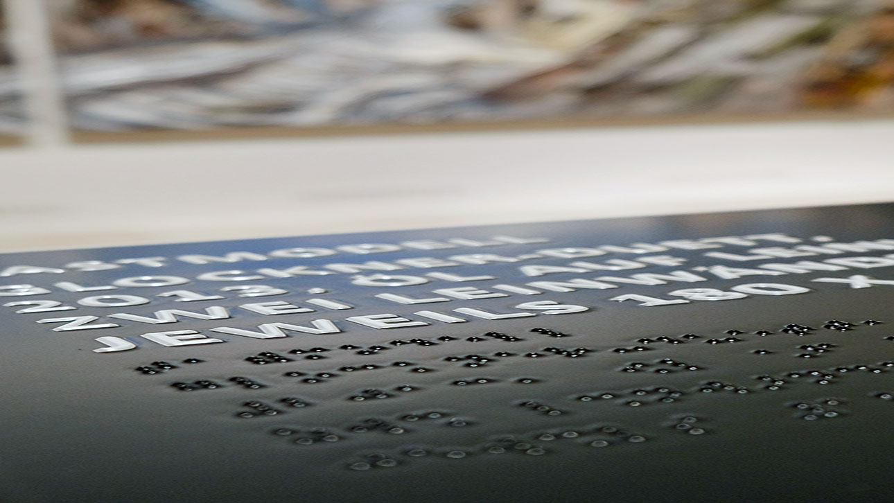 Braille-Schrift ist auf ein Informationsschild gedruckt.
