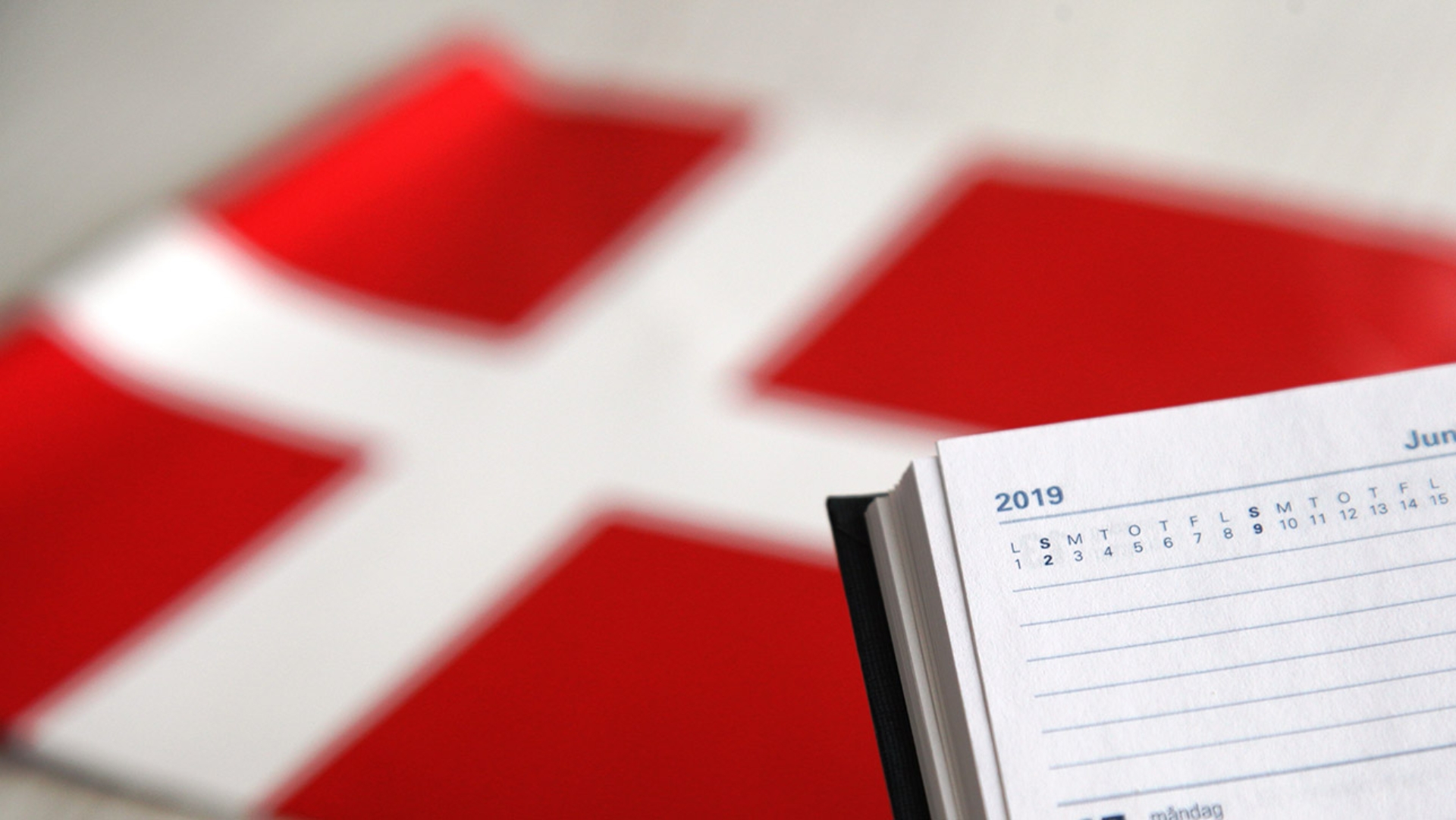 Eine dänische Flagge liegt hinter einem Kalender auf einem Tisch.