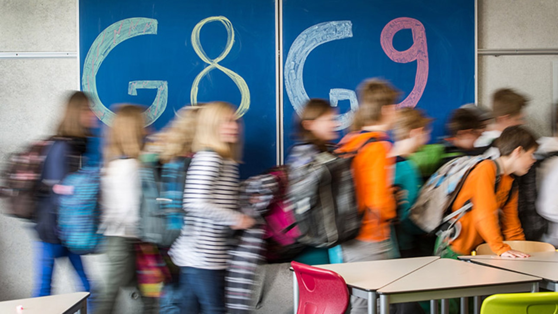 Schüler rennen an einer mit G8 und G9 beschrifteten Tafel vorbei.