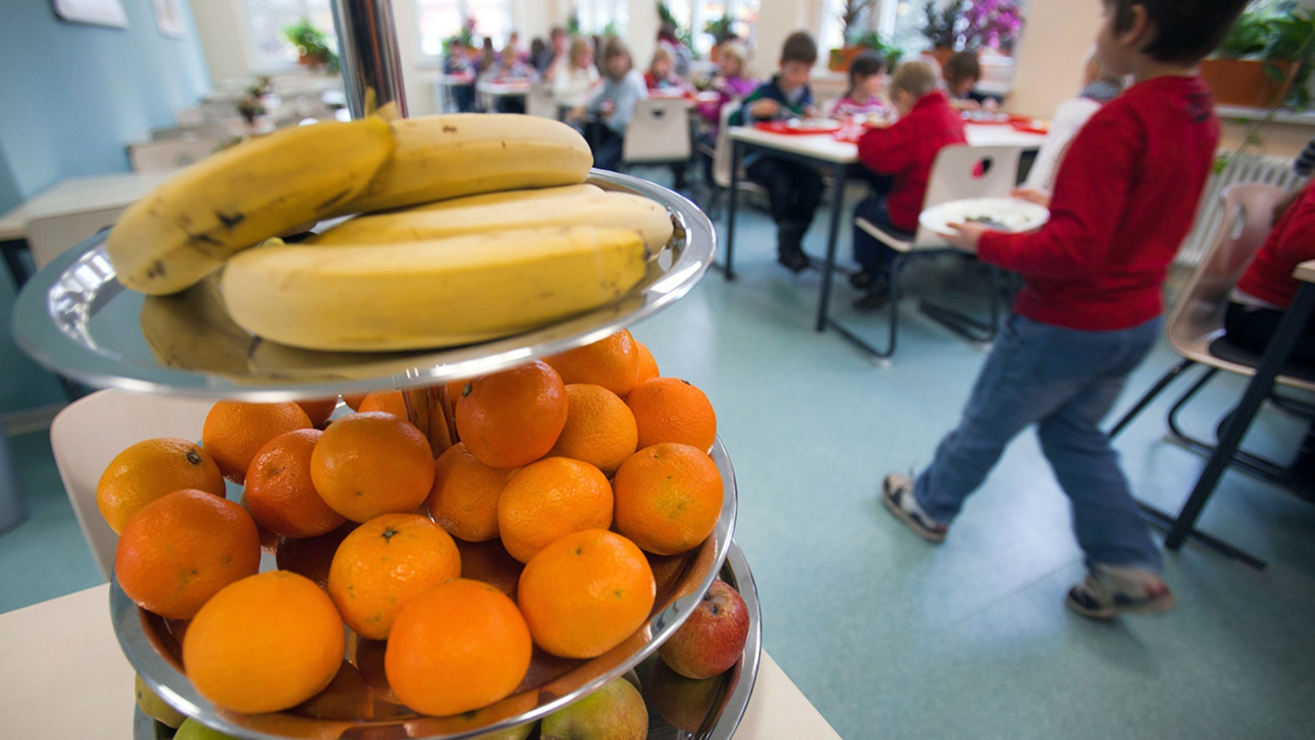 Eine Etagere mit frischem Obst steht während der Mittagspause in der Mensa einer Schulküche.