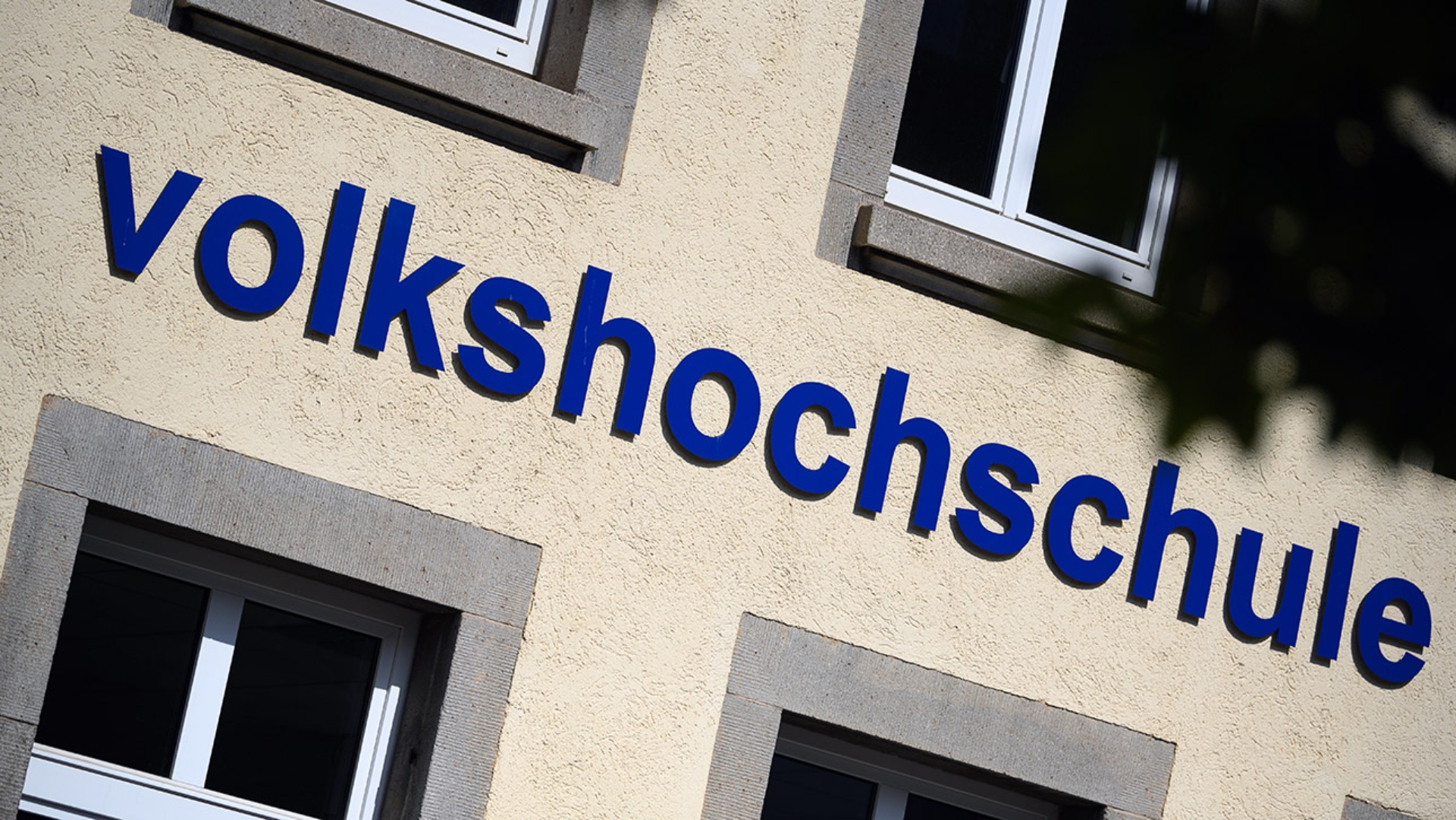 Der Schriftzug "Volkshochschule" ist an einem Gebäude angebracht.