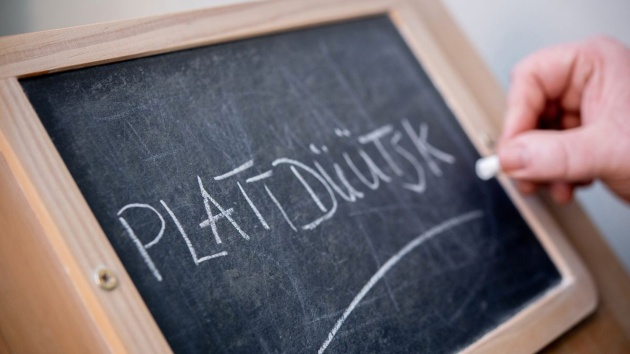 Ein Mann schreibt im Plattdüütskbüro der Ostfriesischen Landschaft das Wort «Plattdüütsk» mit Kreide auf eine Tafel.