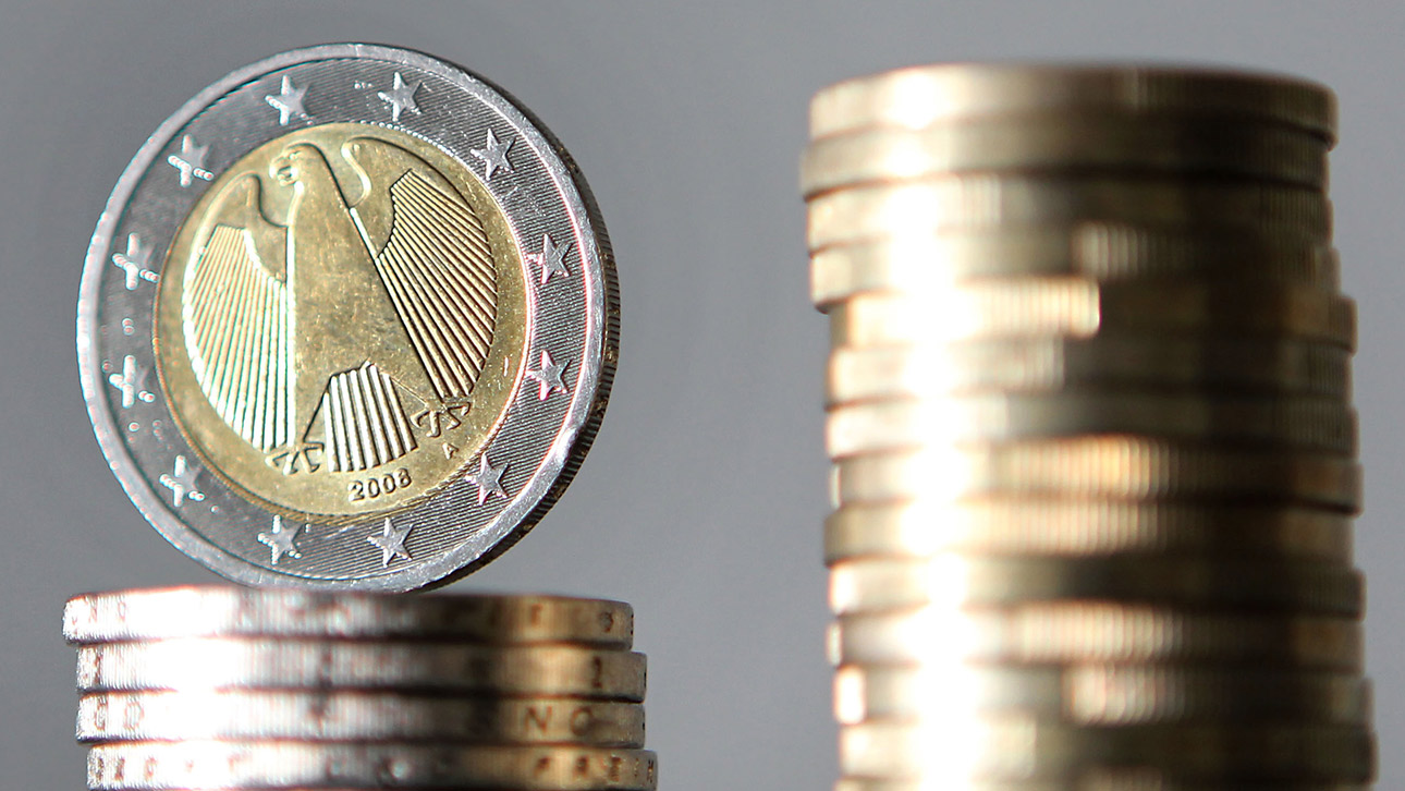 Zwei Stapel Zwei-Euro_Münzen sind vor schwarzem Hintergrund zu sehen.