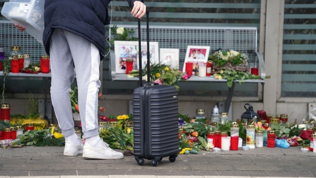 Eine Reisende schaut sich die Blumen, Kerzen und verschiedene Bilder im Wartehäuschen am Bahnhof zum Gedenken an die Opfer der Messerattacke an.