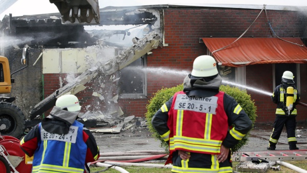 Feuerwehr Illustration Juni 2018 © Foto: dpa, Bodo Marks Feuerwehrleute löschen einen Großbrand in einer Halle in einem Gewerbegebiet in Bad Segeberg und reißen dabei mit einem Bagger die Wand eines Hauses ein.