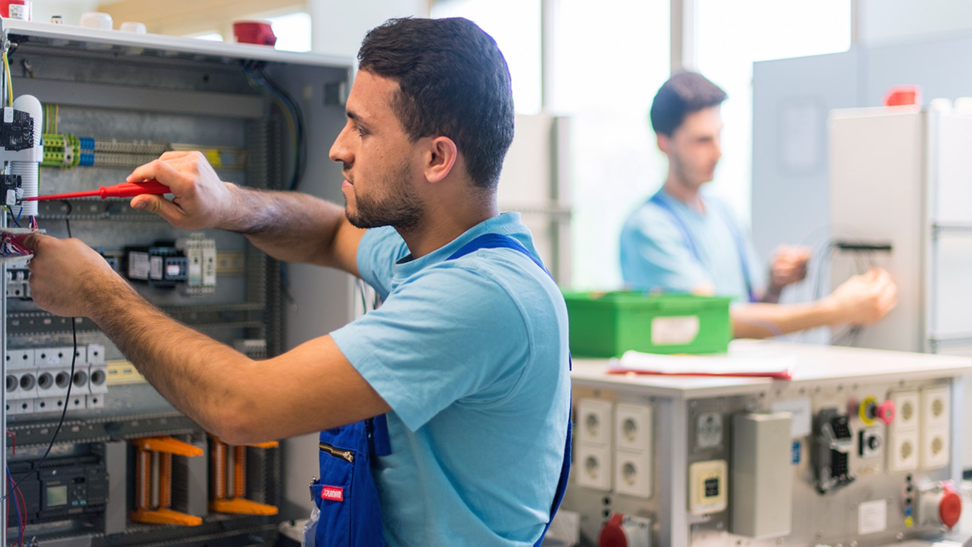 Der 19-jährige Mohammad aus Afghanistan arbeitet im Ausbildungszentrum der Siemens Professional Education an der Verdrahtung eines Schaltschranks.