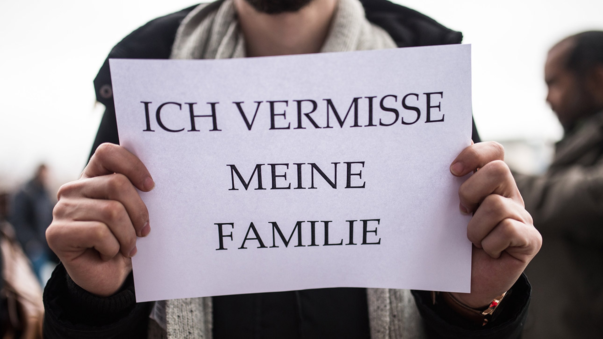 Ein Flüchtling hält ein Schild hoch mit der Aufschrift: „Ich vermisse meine Familie.“