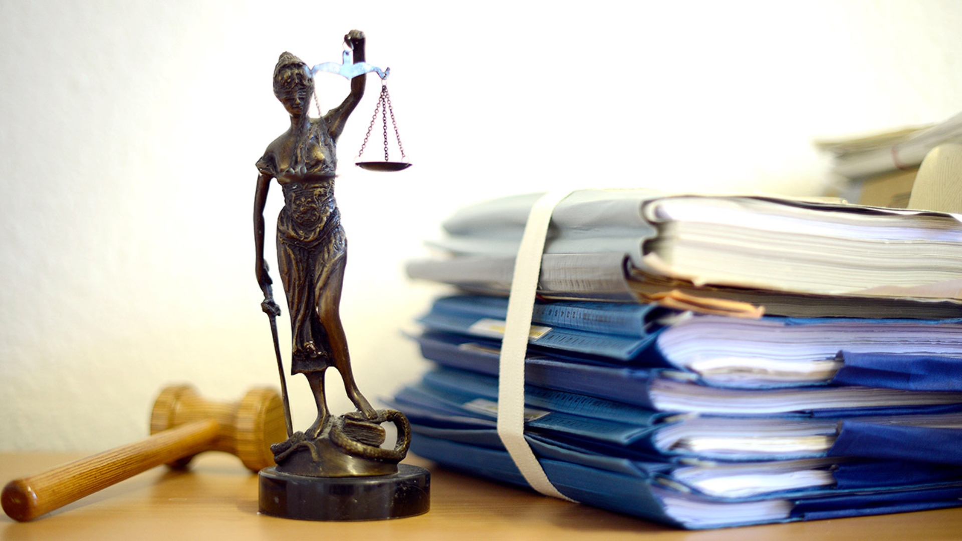 Eine Justizia-Figur mit Akten auf einem Schreibtisch