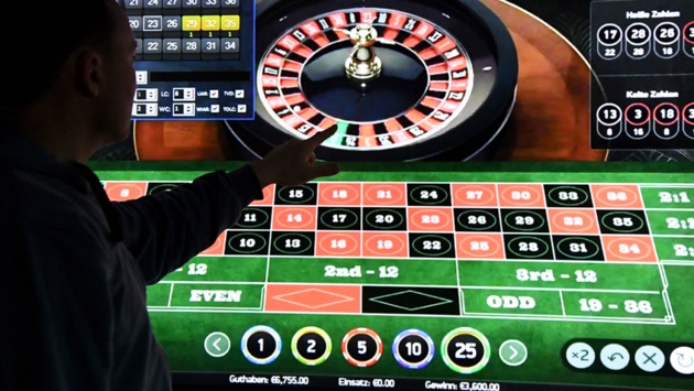 Ein Mann steht vor einem Bildschirm mit einer Seite für Online-Roulette . 