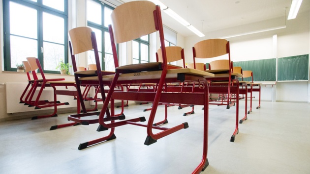 Stühle stehen auf Tischen in einem leeren Klassenzimmer einer Schule.