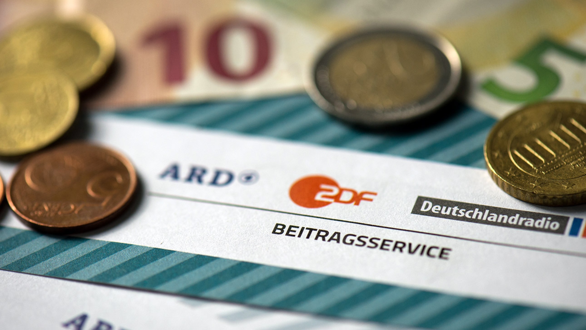 Münzgeld liegt auf Formularen für den Rundfunkbeitrag von ARD, ZDF und Deutschlandradio.