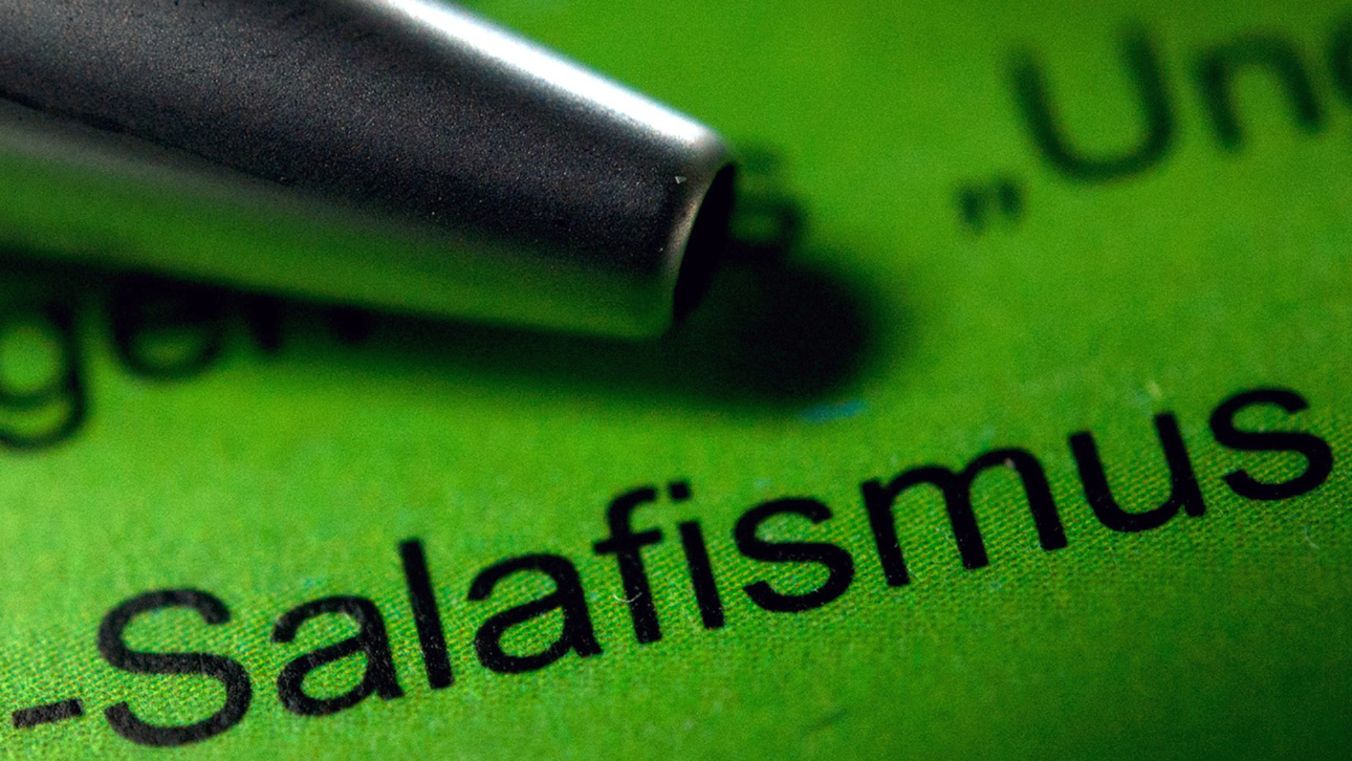 Ein Kugelschreiber liegt auf einem Verfassungsschutzbericht neben dem Schriftzug „Salafismus“.