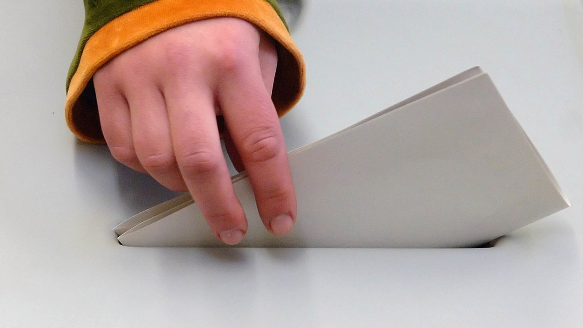 Ein ausgefüllter Stimmzettel wird in eine Wahlurne geworfen.