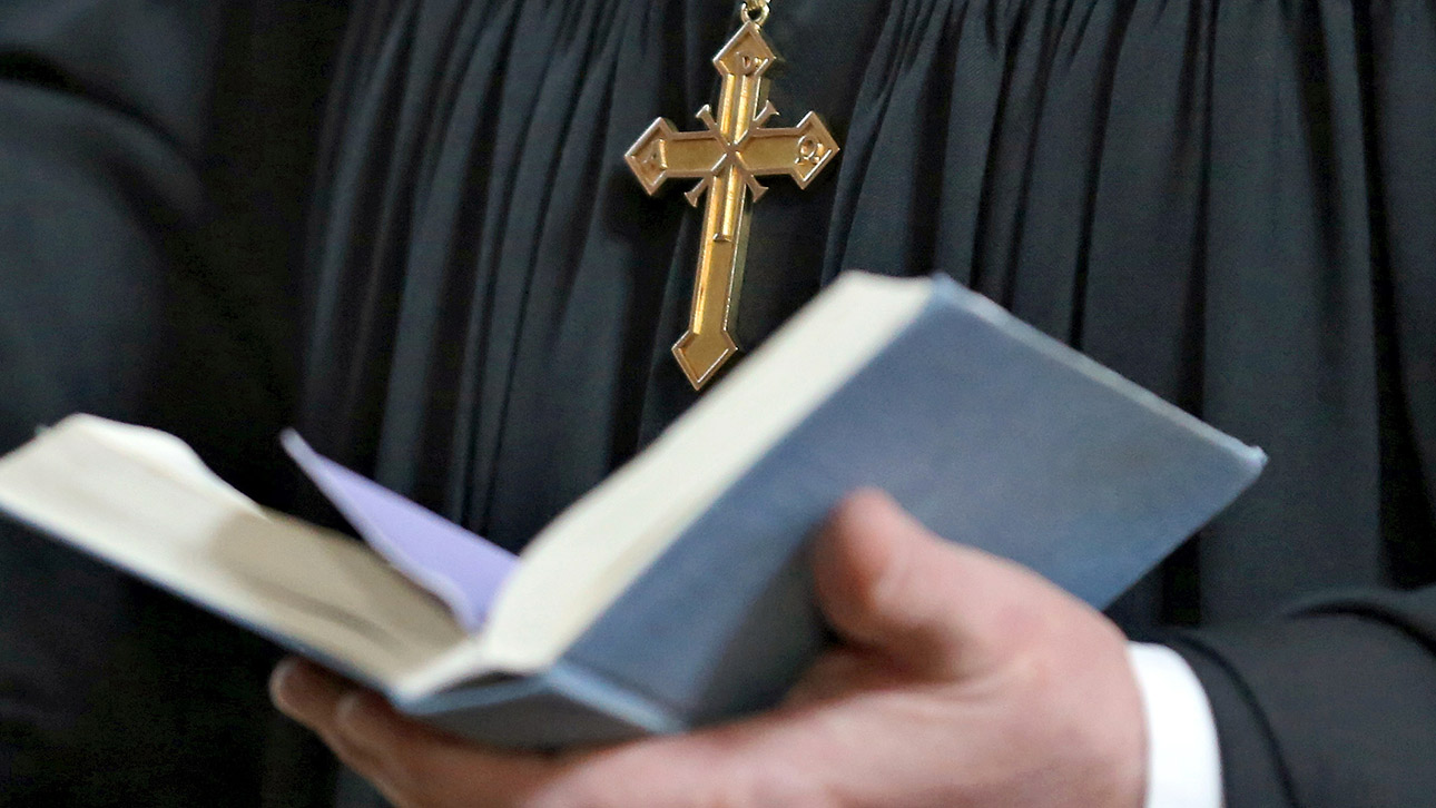 Ein evangelischer Geistlicher hält während eines Gottesdienstes eine Bibel in der Hand. 