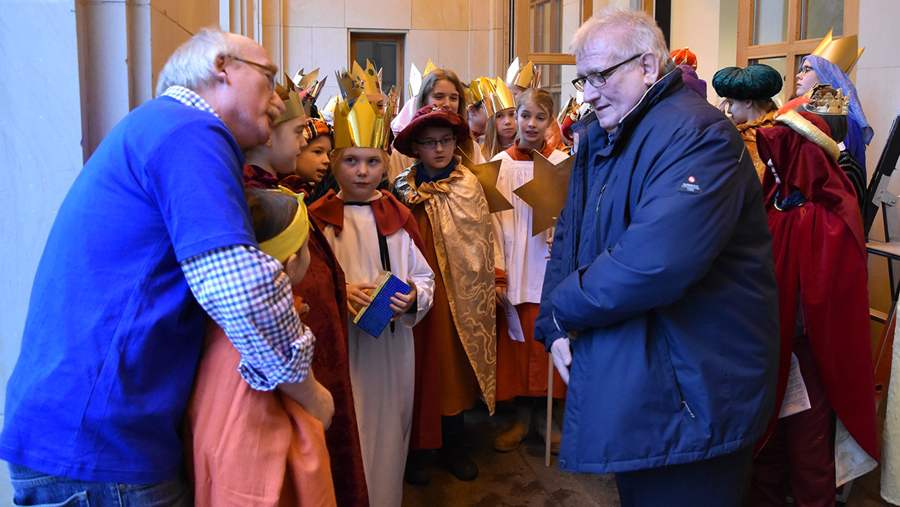 Als Könige verkleidete Kinder stehen vor dem Landtag und werden von Landtagspräsident Klaus Schlie begrüßt.