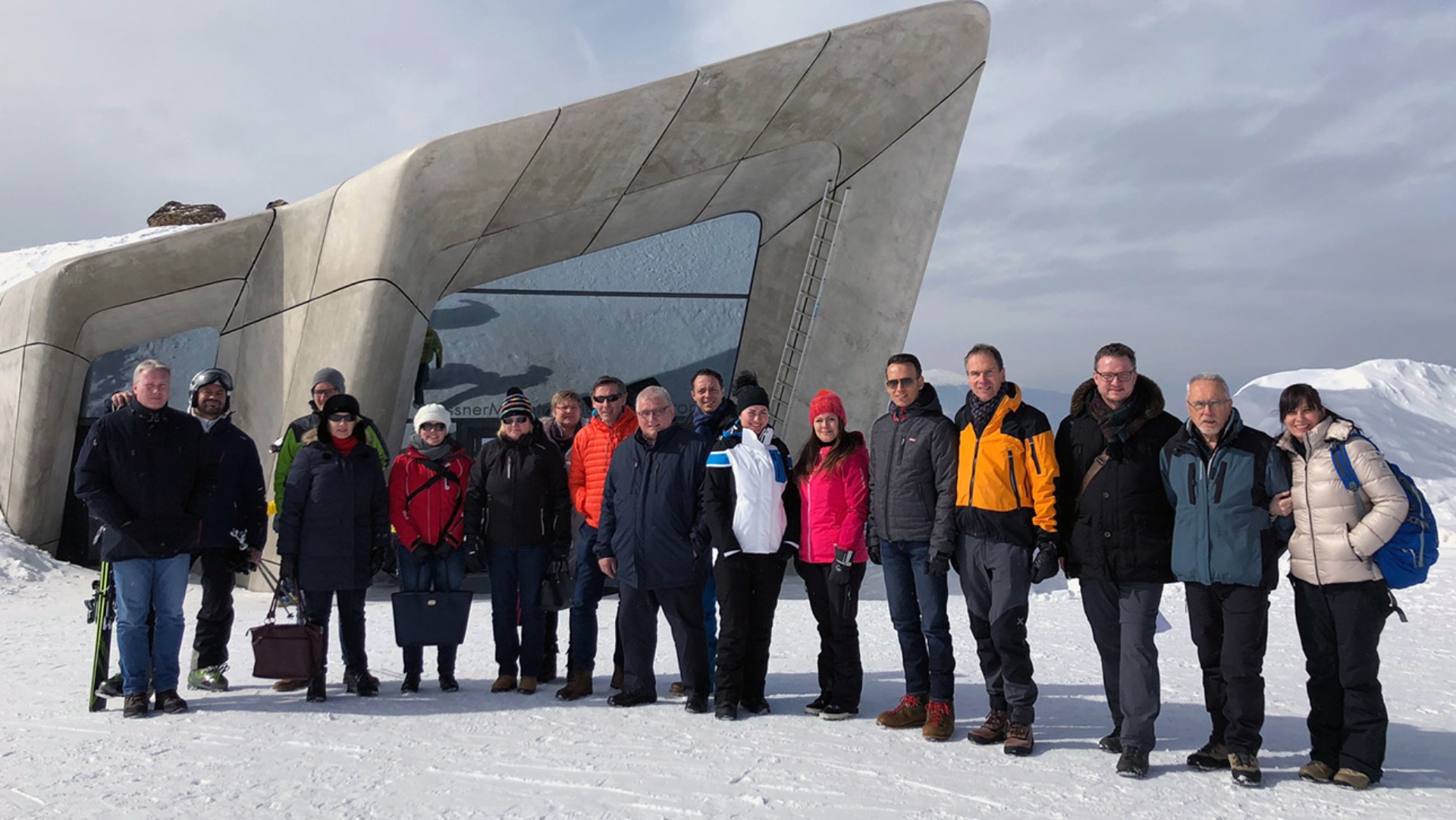 Menschen stehen auf einem Berggipfel vor einem Museum.