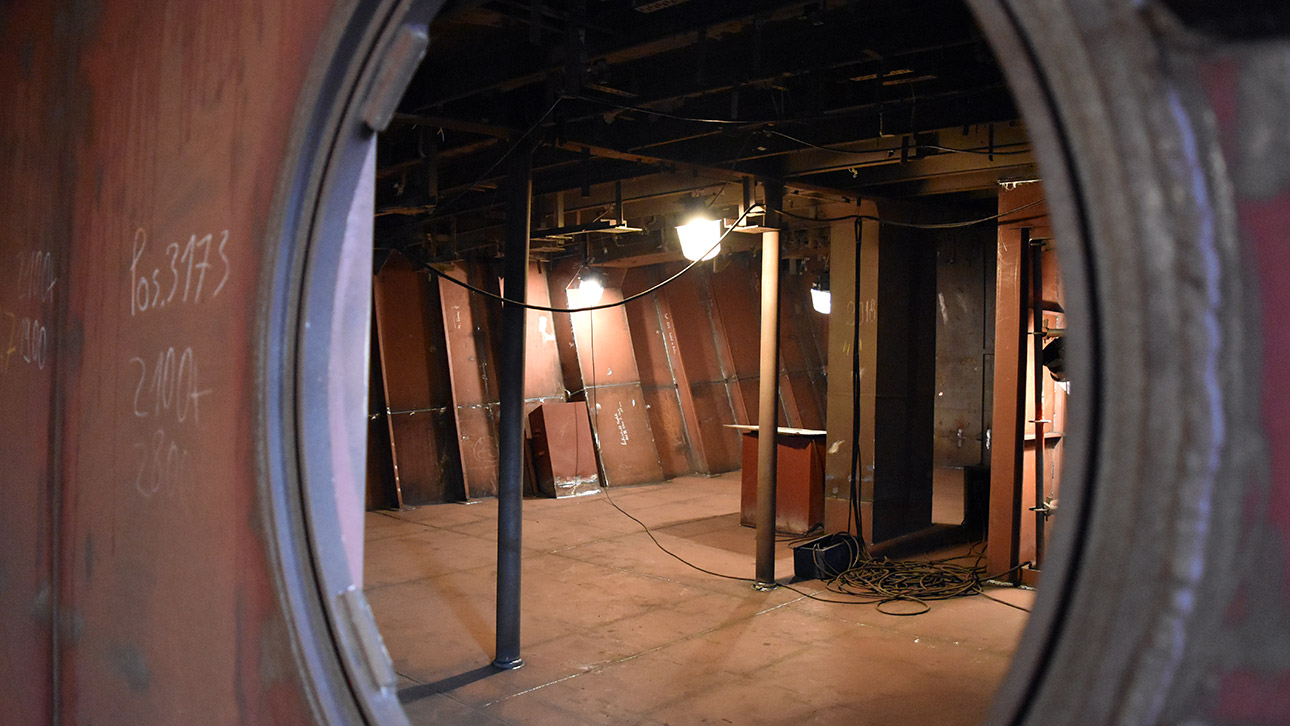 Ein Blick durch ein Bullauge unter Deck auf einen mit Stahl ausgekleideten Raum