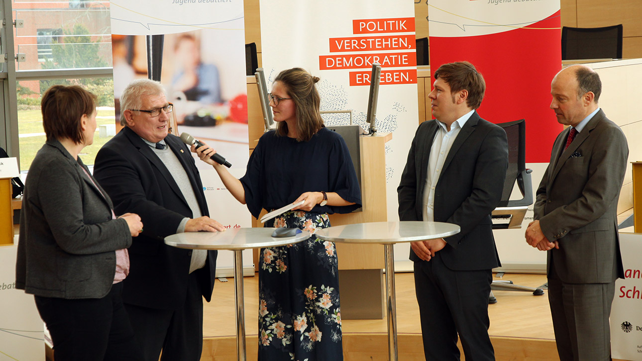 Fünf Menschen stehen um zwei Stehtische herum.