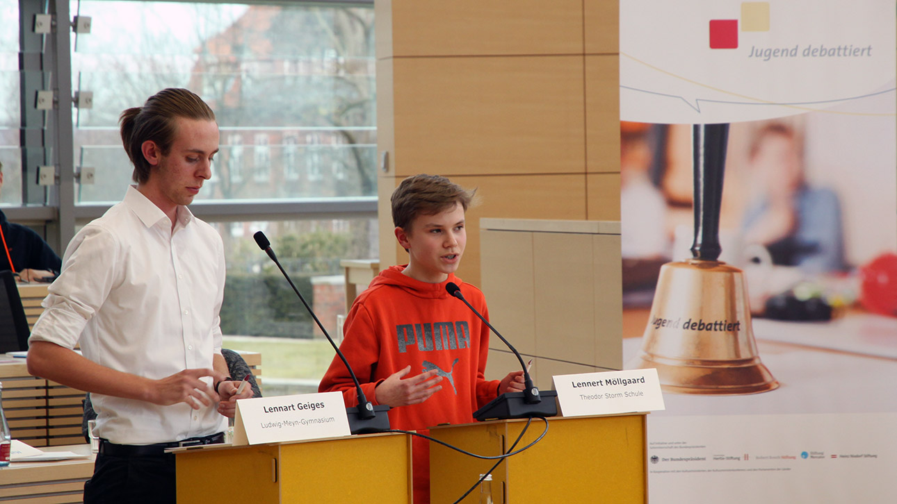 Zwei Jugendliche stehen jeweils an einem Rednerpult und diskutieren.