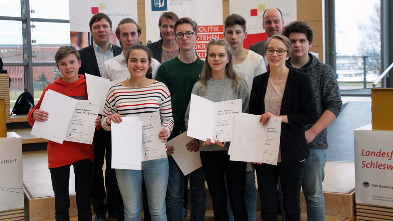 Die Gewinner von Jugend debattiert stehen mit den Ausrichtern des Wettbewerbs im Plenarsaal des Landtages.