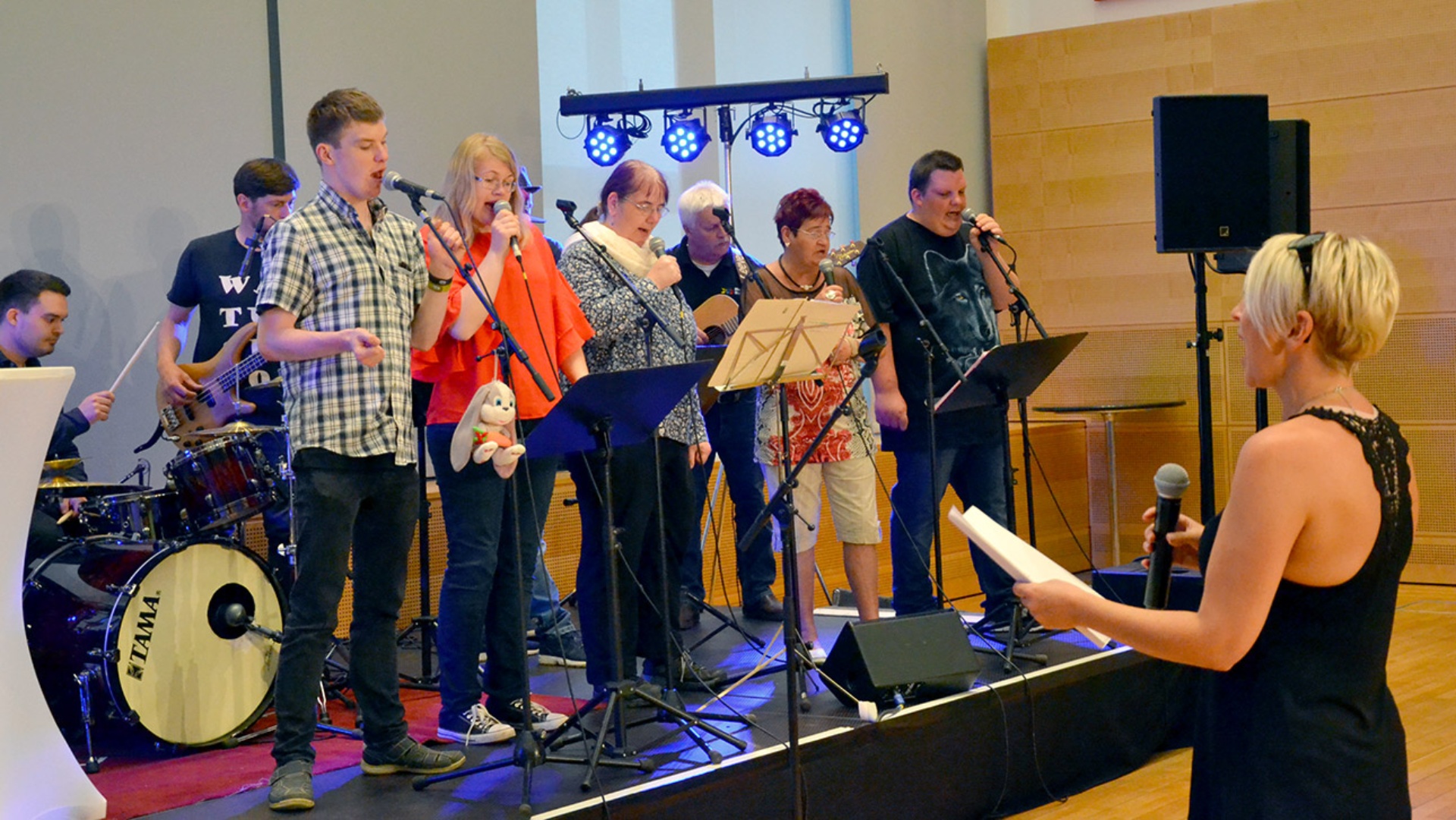 Eine Musikgruppe mit Menschen mit Behinderungen steht auf einer Bühne und musiziert.