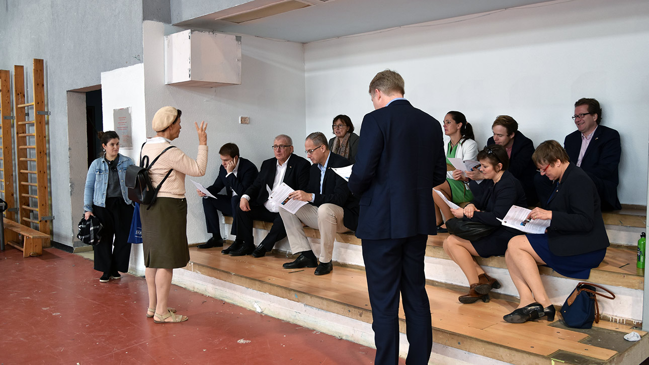 Die Mitglieder des Ältestenrates sitzen auf einer provisorischen Tribüne in einer Turnhalle