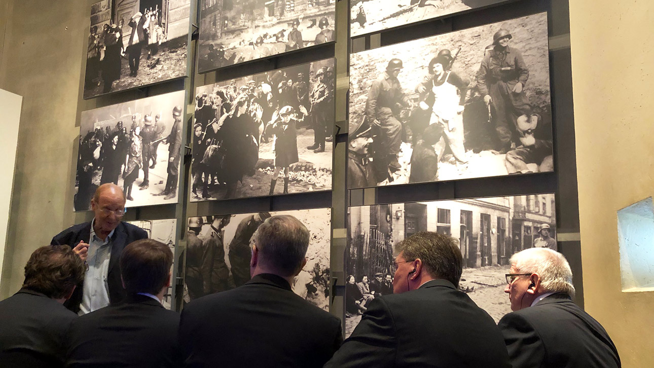 Ein Mitarbeiter des Holocaust-Museums Yad Vashem berichtet den Mitglidern des Ältestenrates vor großen Fototafeln von den Gräueltaten des Nazi-Regimes.
