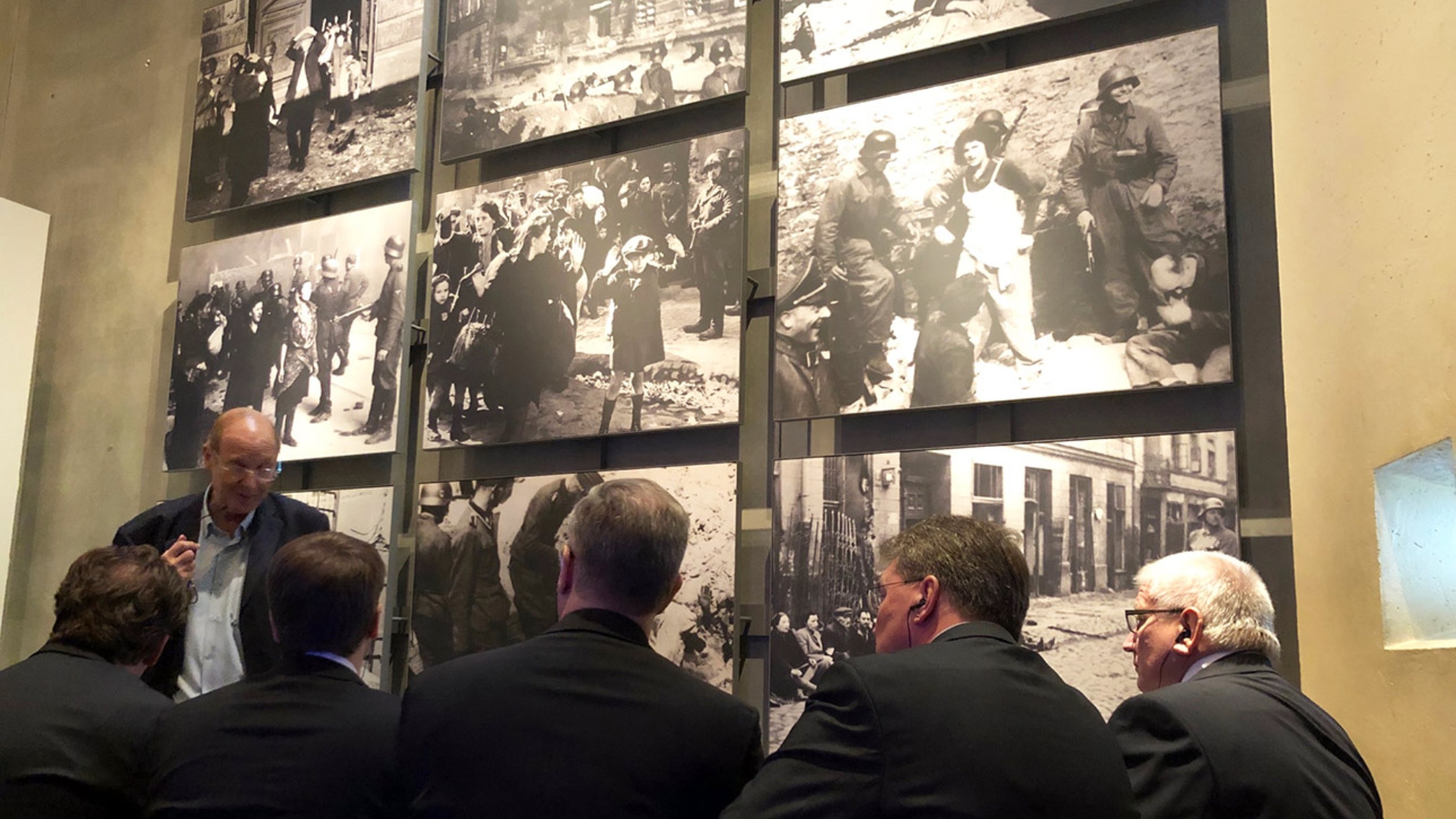 Ein Mitarbeiter des Holocaust-Museums Yad Vashem berichtet den Mitglidern des Ältestenrates vor großen Fototafeln von den Gräueltaten des Nazi-Regimes.