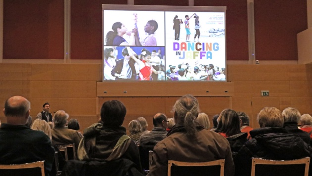 Zuschauer blicken auf eine Leinwand im Schleswig-Holstein-Saal, auf der der Film „Dancing in Jaffa“ zu sehen ist.