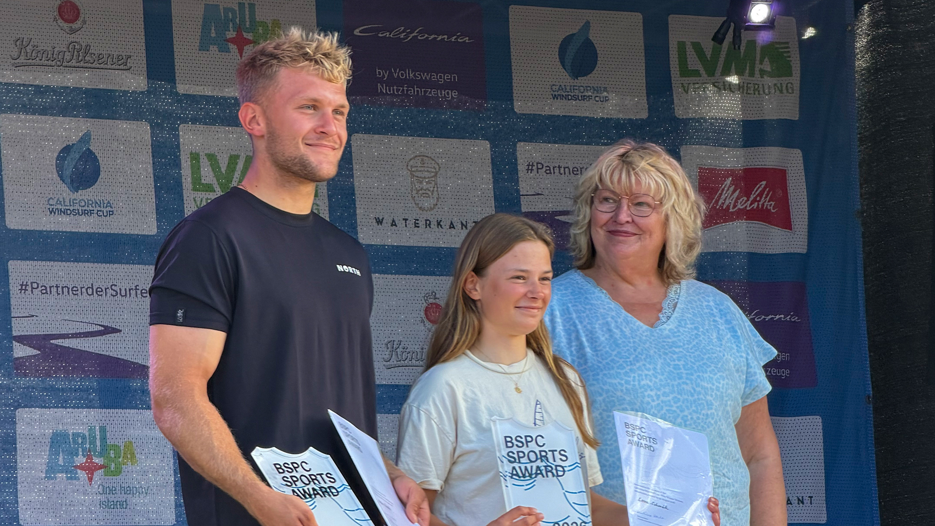 Landtagsvizepräsidentin Jette Waldinger-Thiering mit den Gesamtsiegenden des California Windsurf Cup in Pelzerhaken: Lena Schmäh (Mitte) und Keno Recke