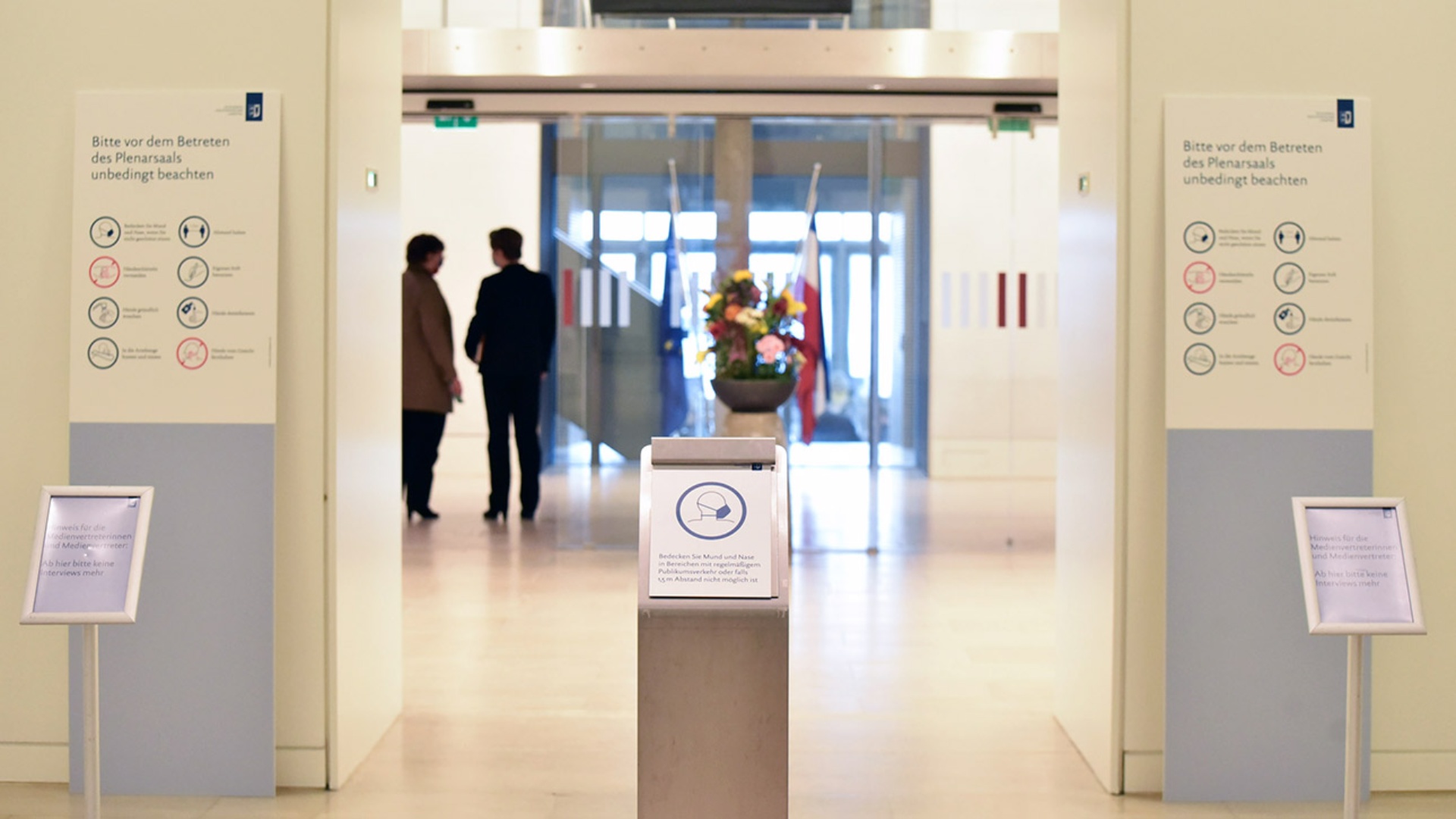 Mit Blick Richtung Plenarsaal sind verschiedene Corona-Hinweisschilder zu sehen.