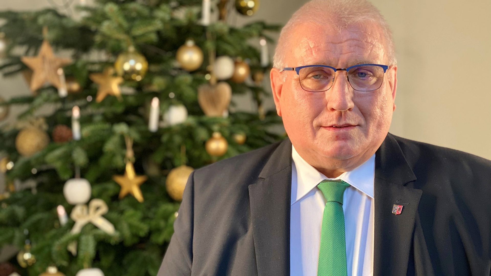 Landtagspräsident Klaus Schlie steht vor einem geschmückten Weihnachtsbaum im Landeshaus in Kiel.