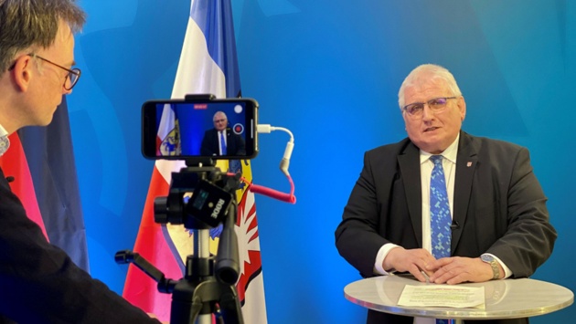 Landtagspräsident Klaus Schlie antwortet auf eine Frage von Jan Schlürmann. Auf einem Stativ ist ein Smartphone, das das Gespräch aufzeichnet.