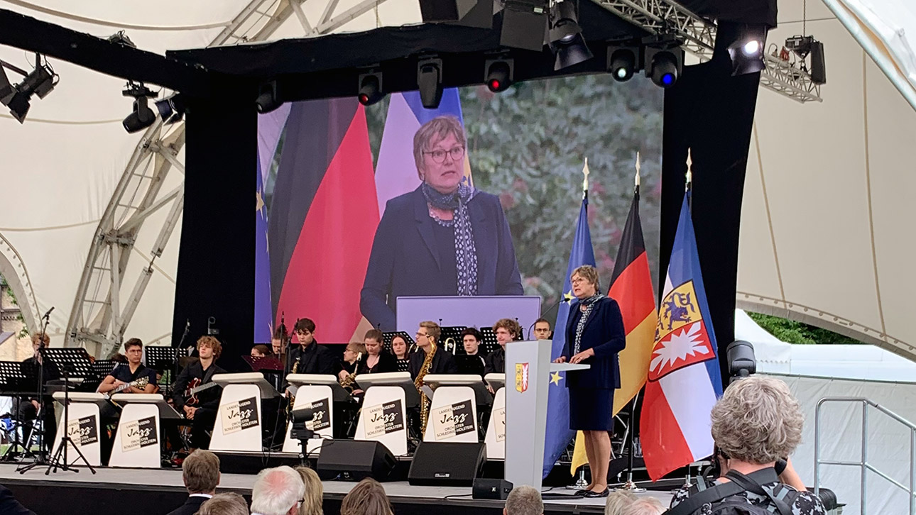 Auf dem Festakt zur 75-Jahr-Feier des Landes Schleswig-Holstein hält Landtagsvizepräsidentin Kirsten Eickhoff-Weber eine Festrede. Im Hintergrund ist ihr Konterfei auf einer großen Leinwand zu sehen.
