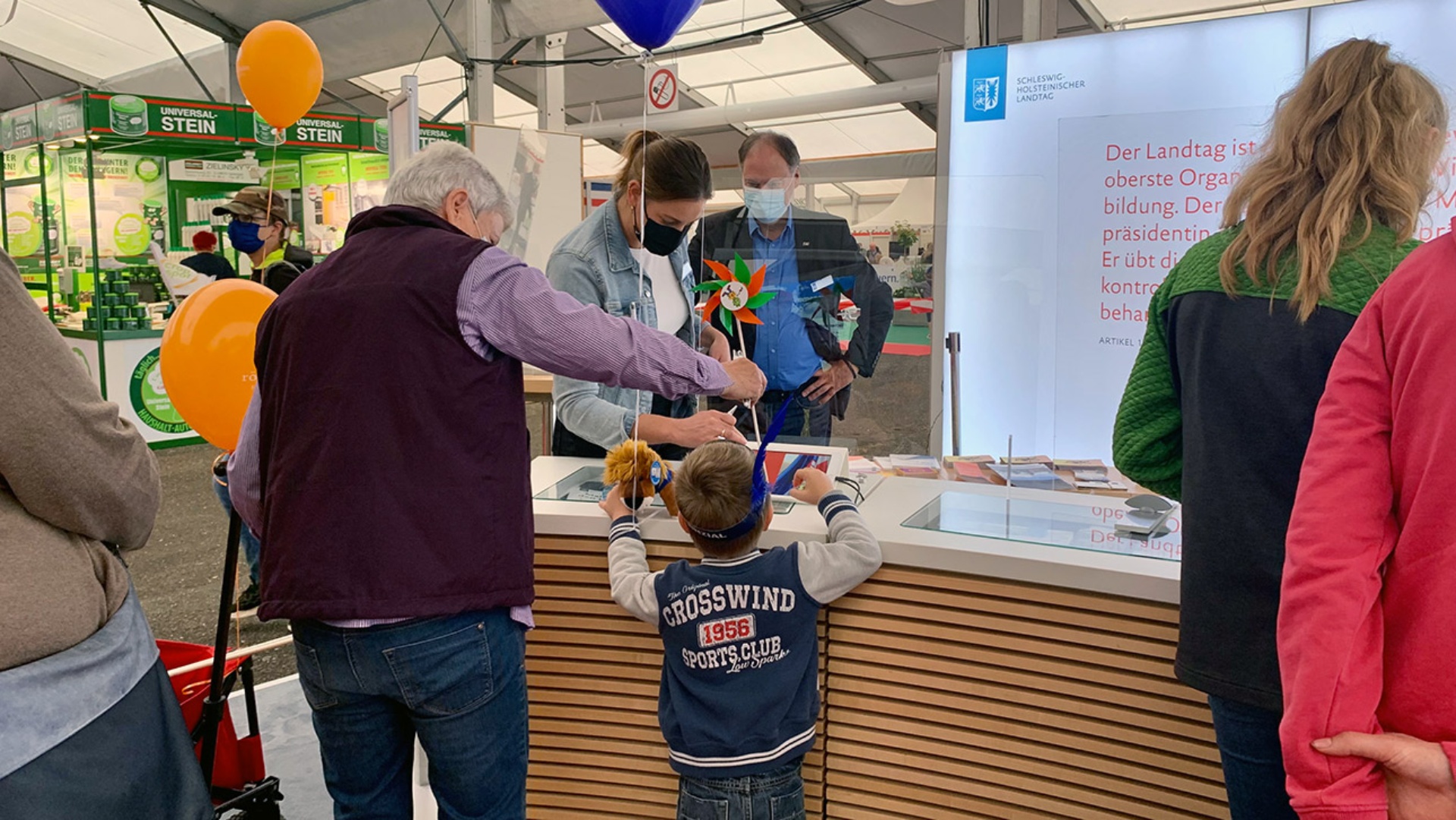 Besucher im Gespräch am Messestand des Landtages