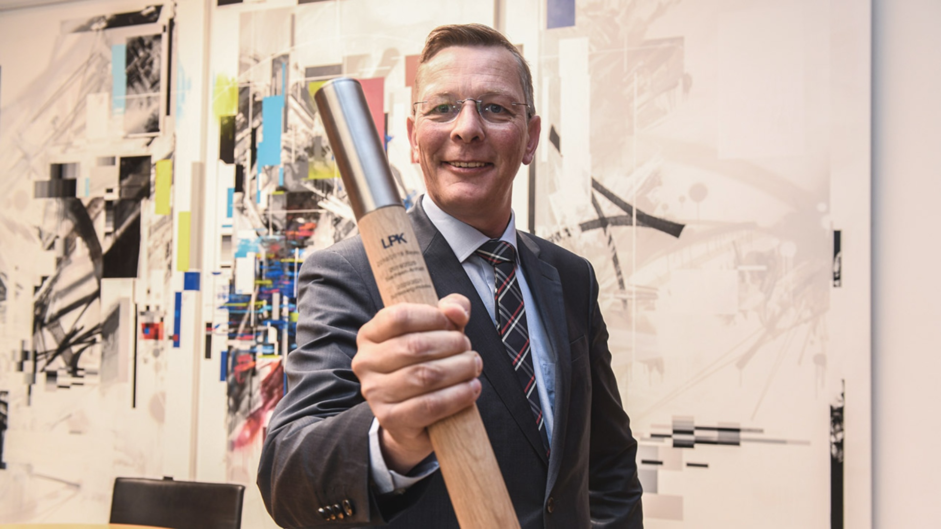 Bürgerschaftspräsident Frank Imhoff hält einen Staffelstab hoch, der symbolisch für die Übernahme des Vorsitzes der Landtagspräsidentenkonferenz steht. 