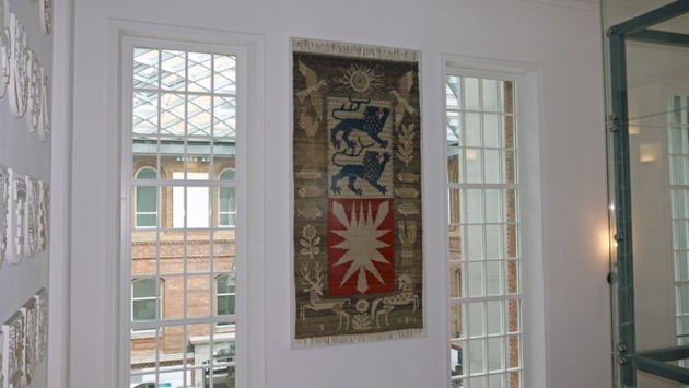 Wandteppich mit Landeswappen hängt am Treppenaufgang im Landeshaus.